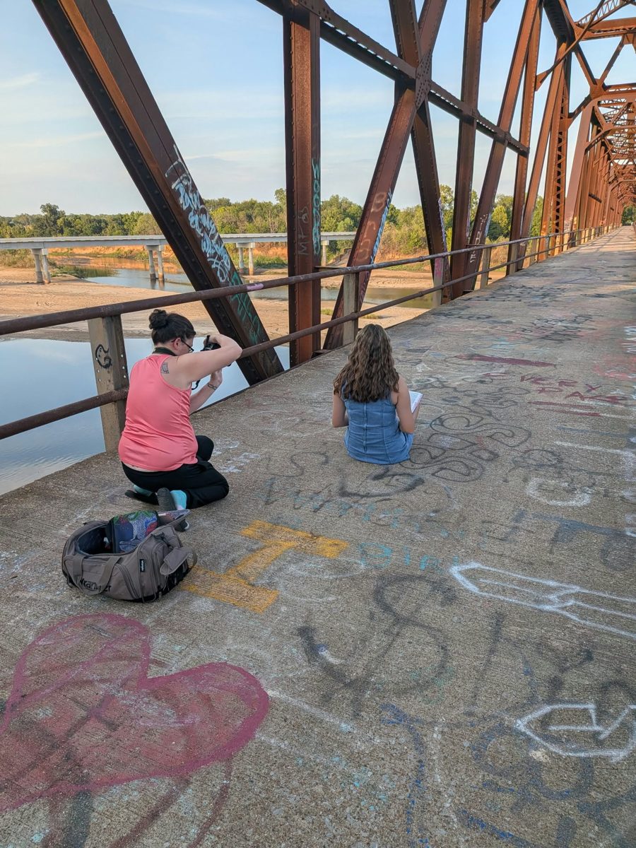 Jennifer kneeling to photograph a client on the bridge
